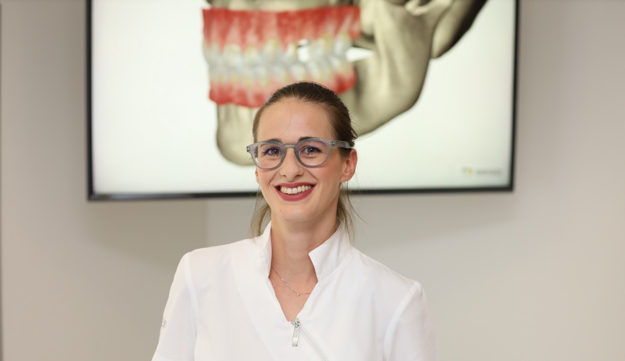 Nasmiješena doktorica u stomatološkoj ordinaciji zrači povjerenjem i toplinom, stvarajući ugodnu atmosferu za pacijente.