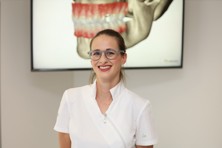 Nasmiješena doktorica u stomatološkoj ordinaciji zrači povjerenjem i toplinom, stvarajući ugodnu atmosferu za pacijente.