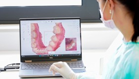 Doktorica u kirurškoj opremi pažljivo proučava 3D sken čeljusti na računalnom ekranu, pripremajući se za zahvat.