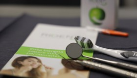 Četkica za zube na pultu uz uredno posložene dentalne instrumente, pripremljene za stomatološki pregled.