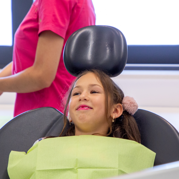 Dijete sjedi na stomatološkoj stolici i strpljivo čeka početak pregleda u ugodnom ambijentu ordinacije.