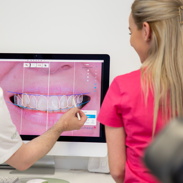 Doktor pokazuje pacijentu Digital Smile Design na ekranu, objašnjavajući virtualni prikaz budućeg osmijeha prije početka terapije.
