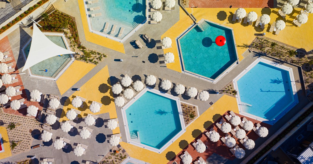 Top-down view of hexagonal pools, loungers, and parasols forming a geometric layout at Aminess Style Camping Atea Resort.