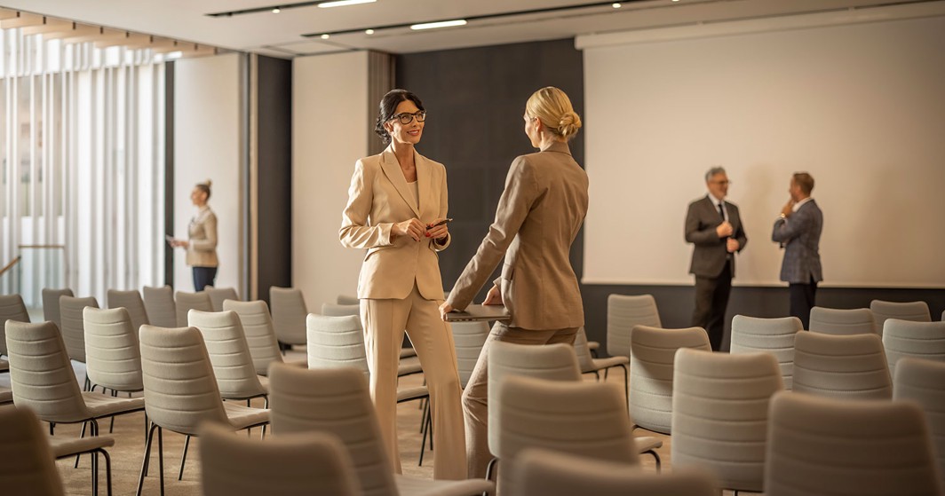 Zwei Frauen unterhalten sich in einem Kongresssaal im Aminess Laurel Khalani Hotel.