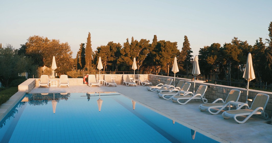 Vanjski bazen s ležaljkama i suncobranima u Aminess Vival Velaris Resortu na otoku Braču, idealan za opuštanje uz zalazak sunca u mirnoj mediteranskoj atmosferi.