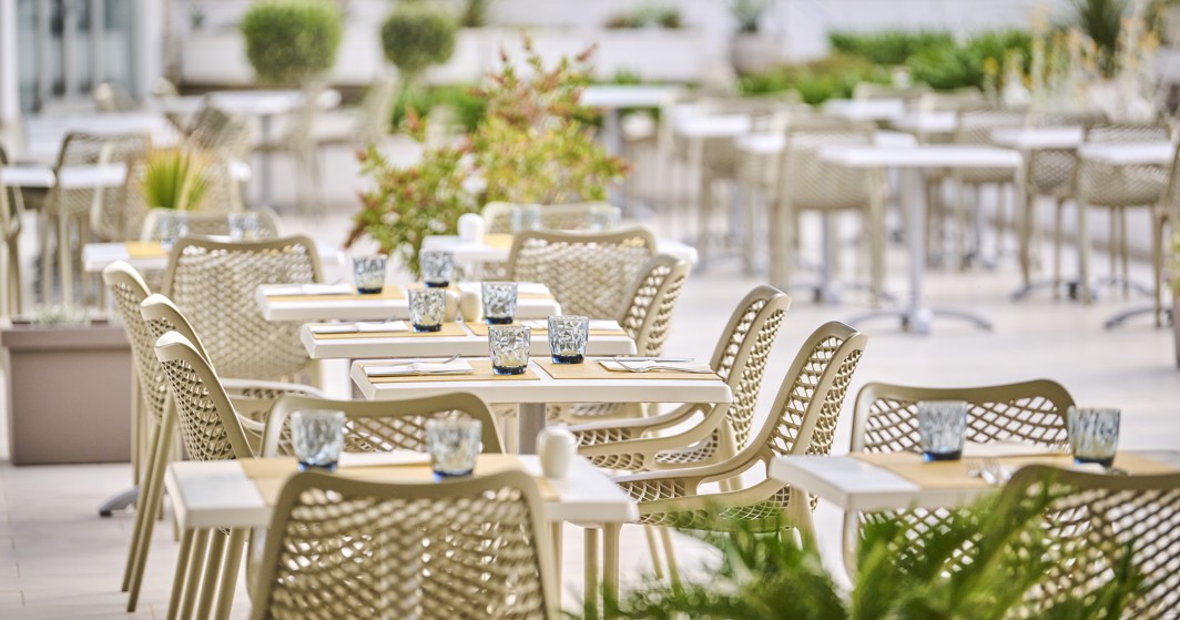 A table set with plates, cutlery, and glasses on the terrace, with a beautiful view of the surrounding area within resort near Aminess Vival Port9 Residence.