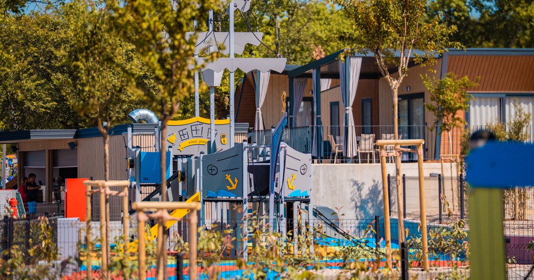 Parco giochi a tema nave dei pirati, circondato da verde e case mobili presso l'Aminess Style Camping Atea Resort.