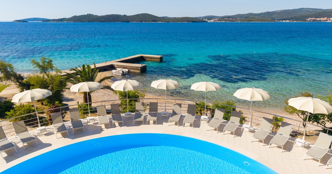 Pool at Orsan Maradiso Hotel by Aminess with loungers, umbrellas and a sea view.