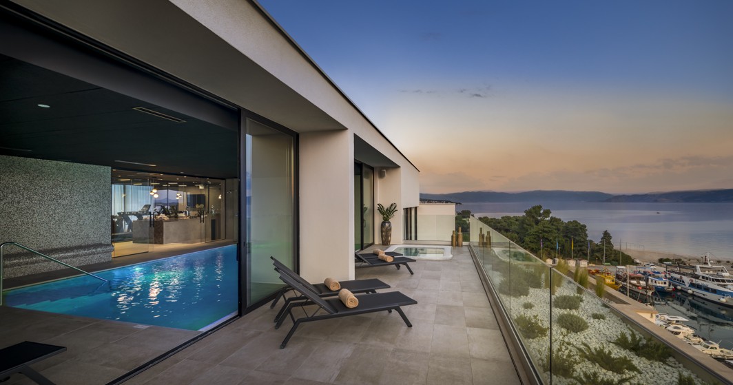 Indoor pool with a sea view at sunset at Aminess Younique Narrivi Hotel.