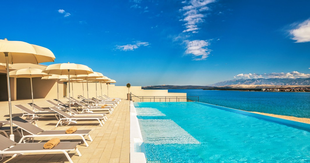 Deck chairs and umbrellas lined up next to the relax pool with sea view at Aminess Style Camping Avalona resort.