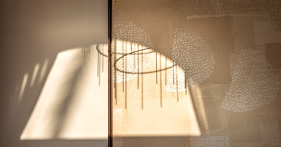 Sunlit chandelier shadow on wall art at Aminess Younique Korcula Heritage Hotel.