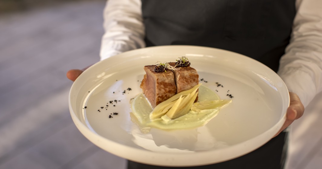 Waiter presenting a gourmet dish at 7 Seas Restaurant in Korcula, featuring seared tuna steak served on a bed of creamy sauce.