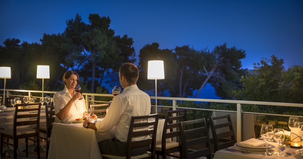 Couple enjoying a candle-lit, night ambience at the restaurant's terrace at Aminess Vival Grand Azur Hotel.