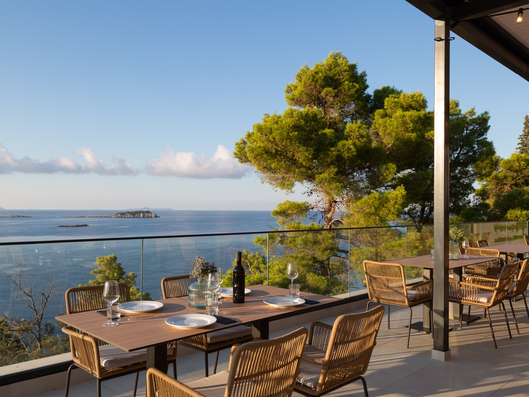 Terasa restavracije v Aminess Alfir Resort z pogrnjenimi mizami in razgledom na morje ter obalo
