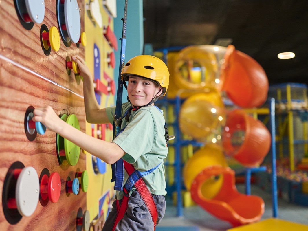Bambino con casco si arrampica su una parete indoor nell area giochi