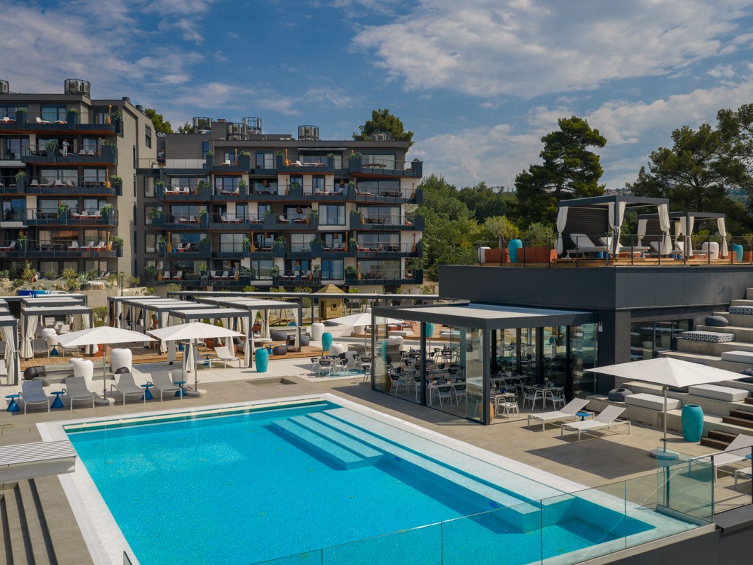 Vanjski infinity bazen s terasama i modernim lounge prostorom u resort okruženju s pogledom na more