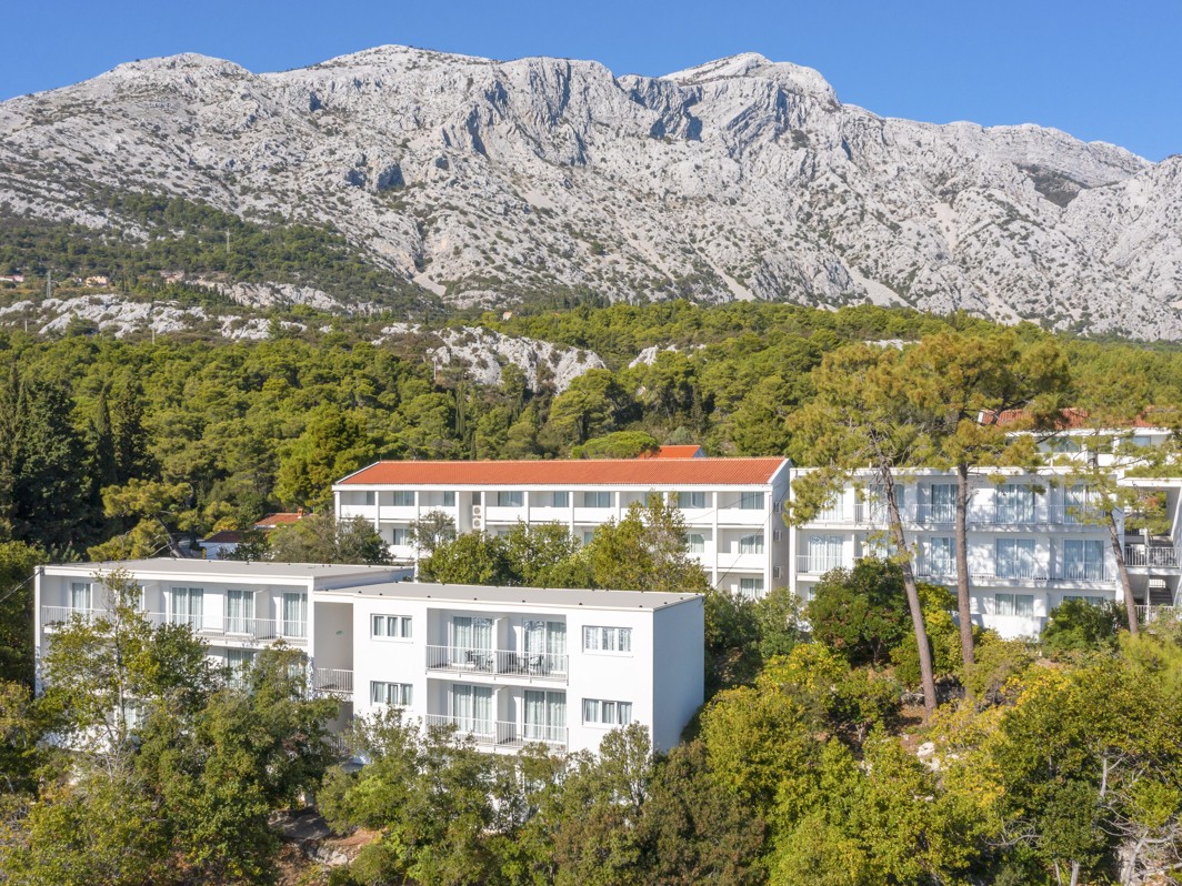 A bird's-eye view of the Aminess Casa Bellevue nestled amidst lush greenery, boasting a private beach and direct sea access.