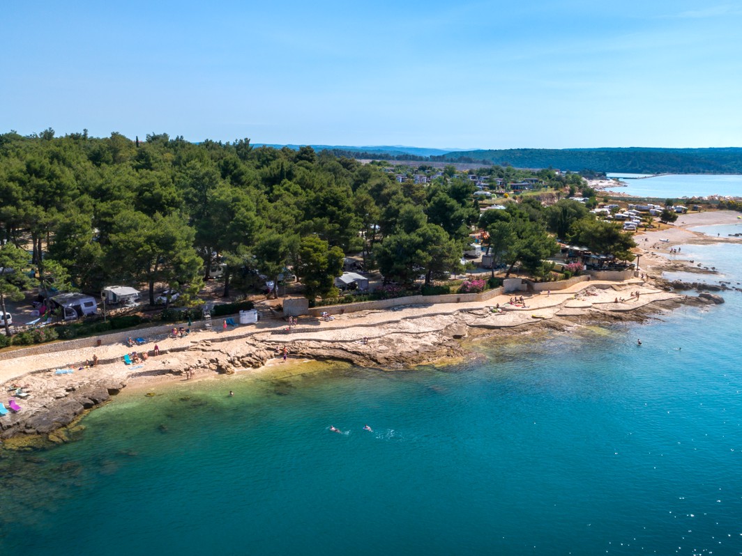 Pogled na uvalu kampa Aminess Sirena u Novigradu s plažom i borovom šumom.