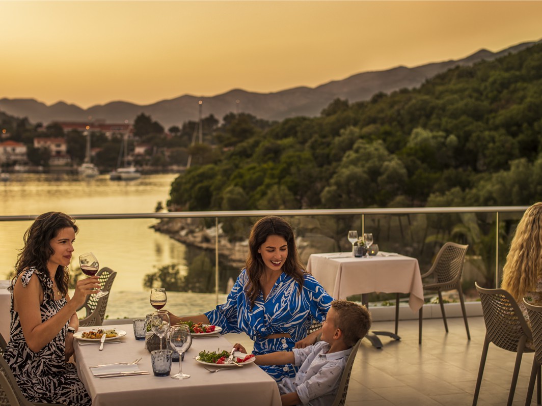 Ospiti che si godono un pasto sulla terrazza del ristorante, con una vista mozzafiato del tramonto all'interno del resort vicino a Aminess Vival Port9 Residence.