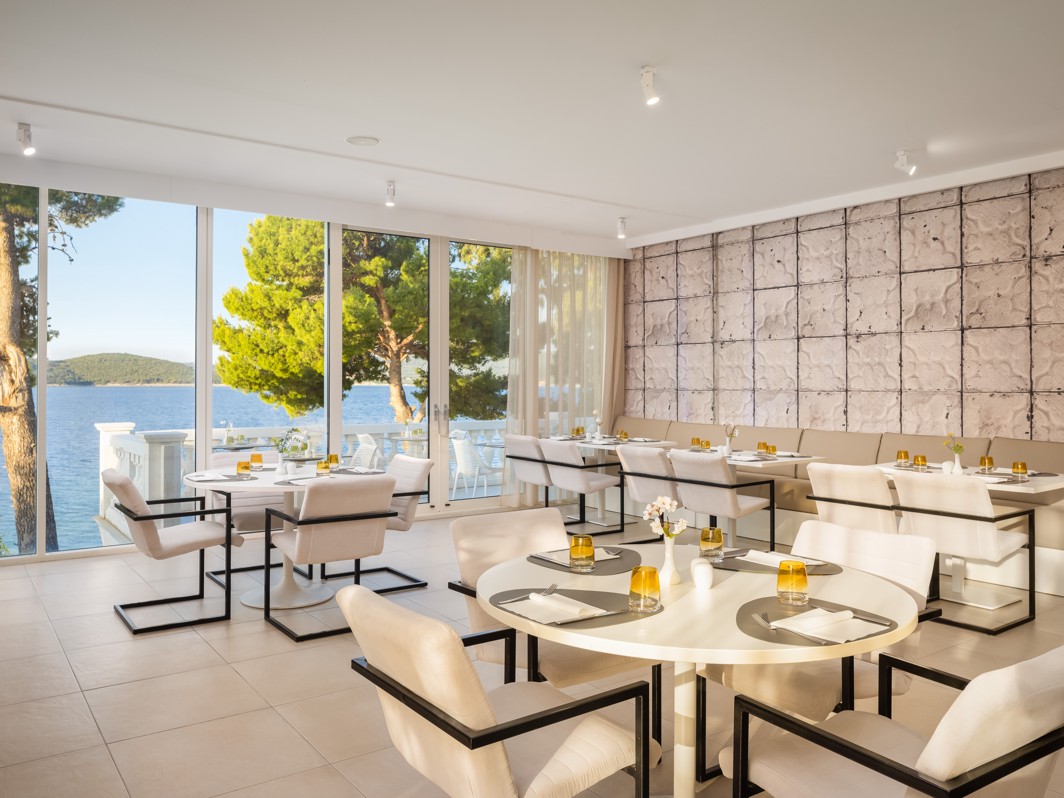 Elegant restaurant at Younique Bellevue Hotel with set tables and a sea view.