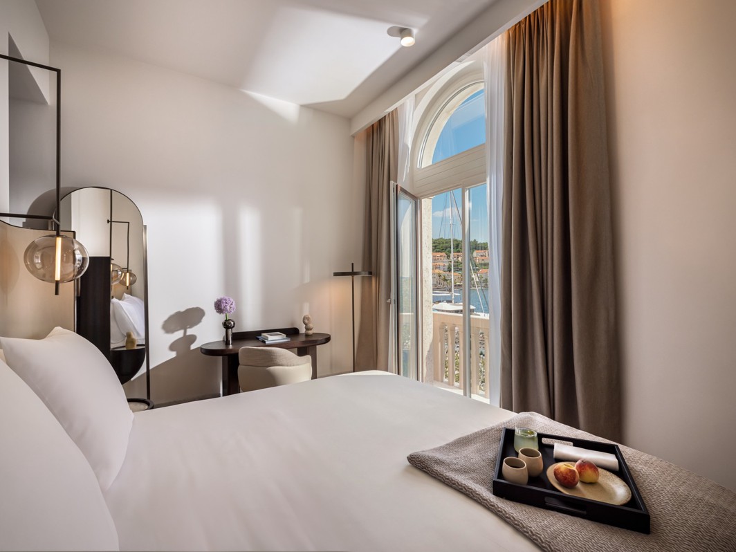 Nowoczesny pokój hotelowy Aminess ze śniadaniem na łóżku i widokiem na marinę.