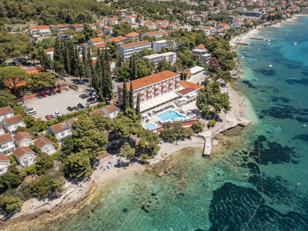 Ein Vogelperspektive auf das Aminess Bellevue Village, eingebettet in üppiges Grün, mit einem privaten Strand und direktem Meereszugang