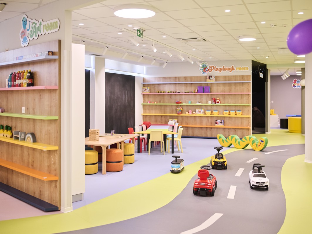 Slika prikazuje hotelsko igralište s različitim aktivnostima i sadržajima za djecu.