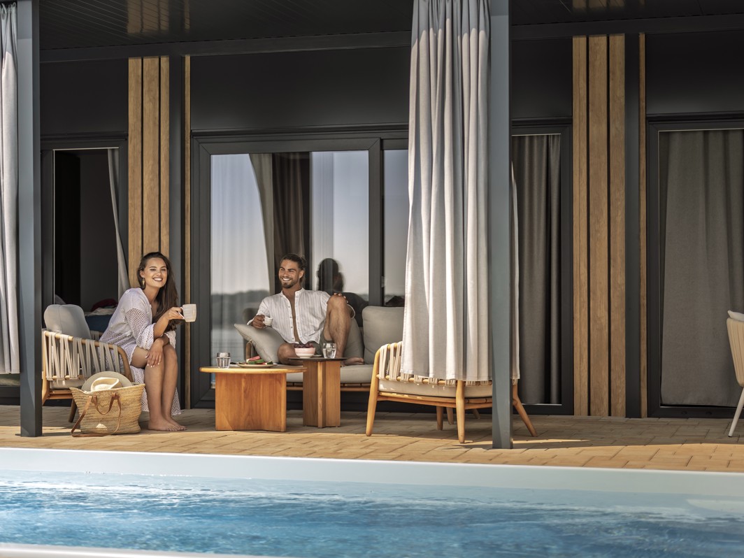 Par se opušta na privatnoj terasi s bazenom u večernjim satima u luksuznoj kućici za odmor u Aminess Camping Sirena.