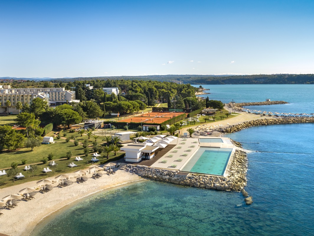 Pogled iz zraka na dežnike, prodnato plažo in morje