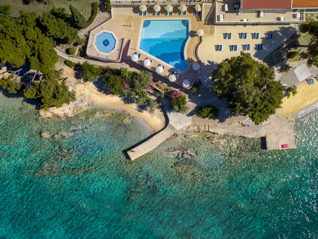 A sun-drenched pool terrace near Aminess Maradiso Casa Bellevue in Croatia, offering stunning sea views and comfortable loungers for relaxation.