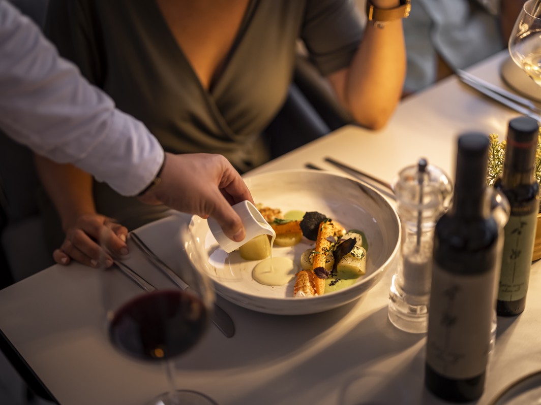 Elegante eetervaring in het 7 Seas restaurant in Aminess Style Camping Atea Resort, met een gastronomisch gerecht dat wordt geserveerd met wijnflessen en glazen op tafel.