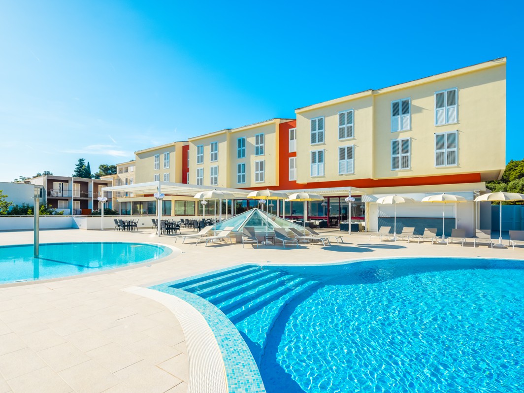 Vanjski pogled na Marko Polo Mardiso Hotel uz bazen, s modernom fasadom i sunčanim vremenom.