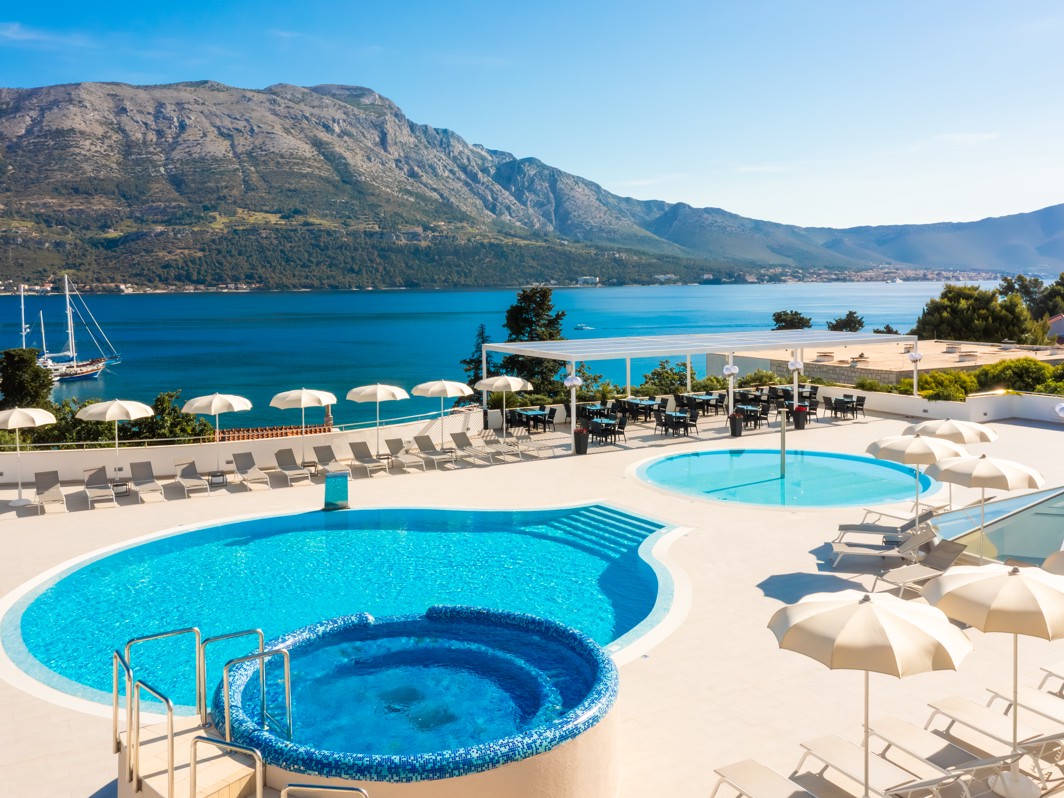 Glavni vanjski bazen hotela Marko Polo Mardiso s ležaljkama i impresivnim pogledom na planine.