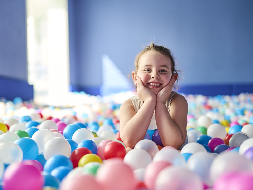 Una bambina sorridente gioca nella piscina di palline colorate nell area bambini