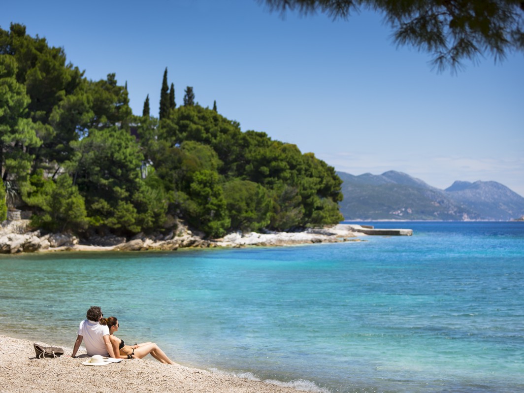 Couple enjyoing sea view on a pebble beach near Aminess Grand Azur Hotel in Orebic.