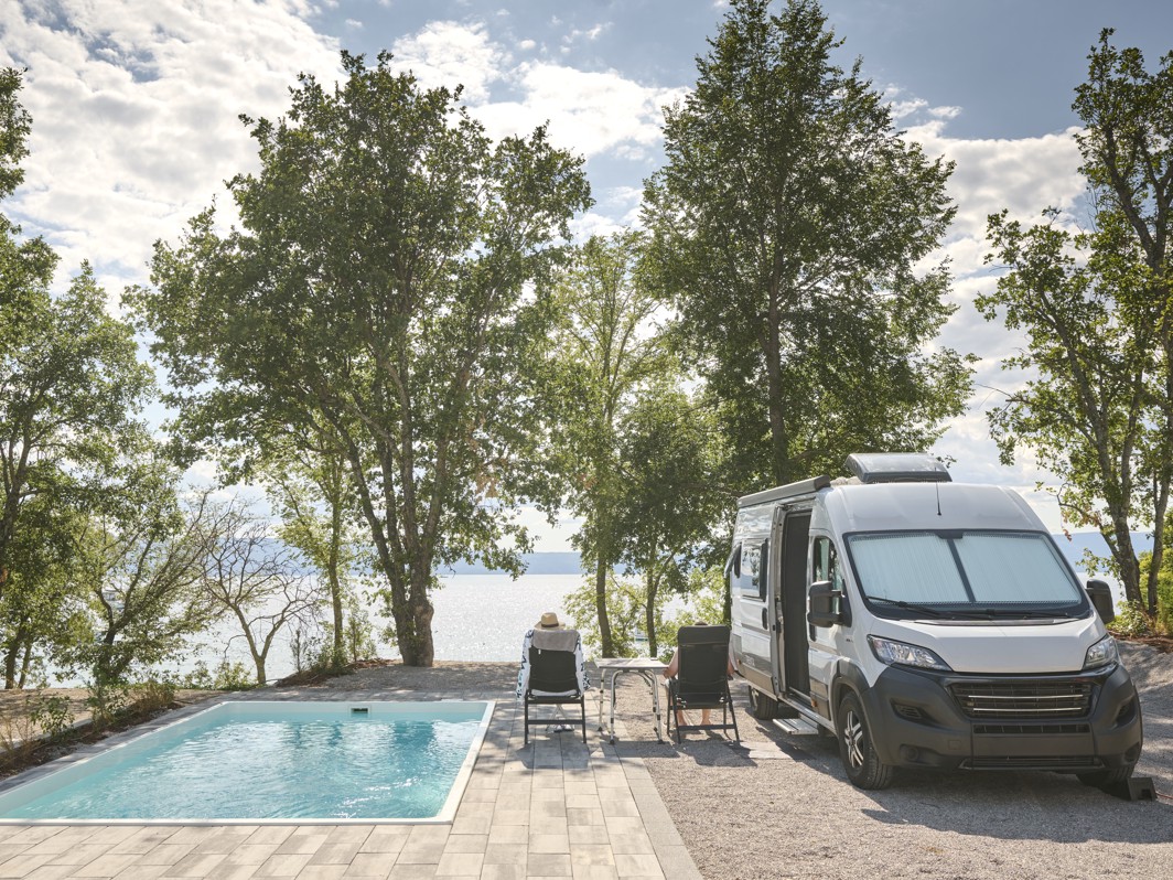 Območje bazena v Aminess Style Camping Atea Resort z ležalniki in bujnim drevesjem.