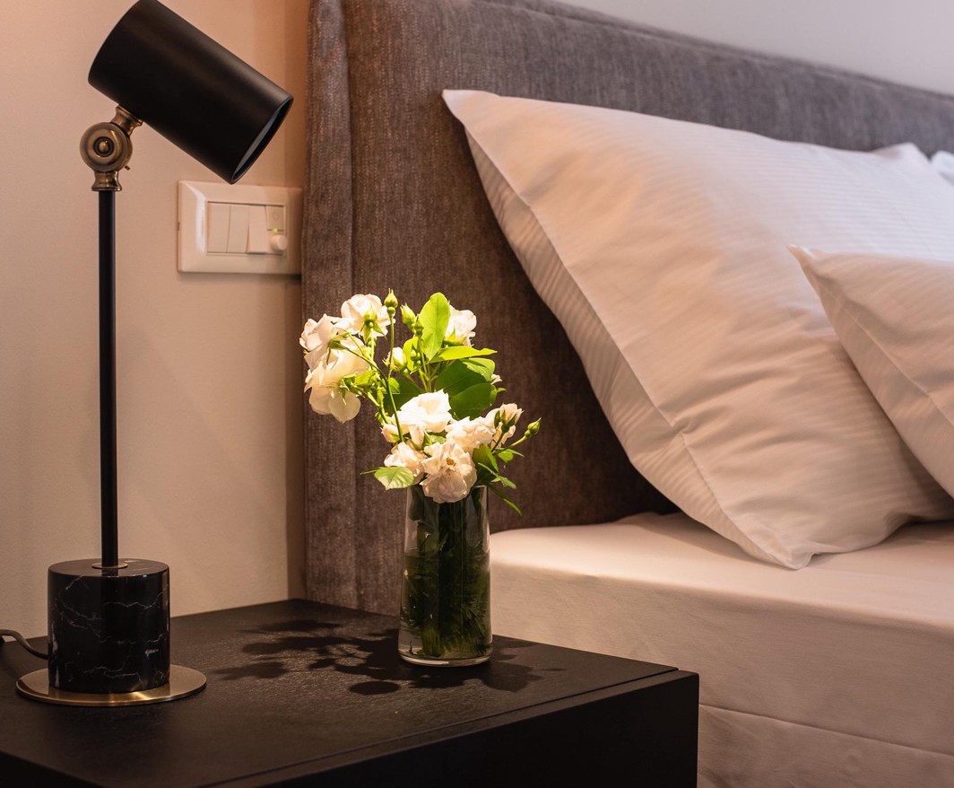 Close-up of bedside table with lamp and flowers in hotel room