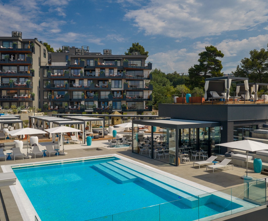 Vanjski infinity bazen s terasama i modernim lounge prostorom u resort okruženju s pogledom na more