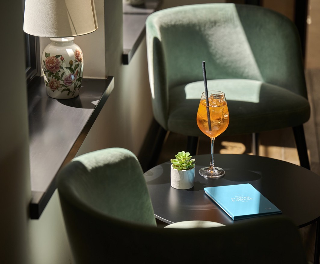 Koktajl obok zielonych foteli w barze lobby Aminess Florian and Godler Hotel.