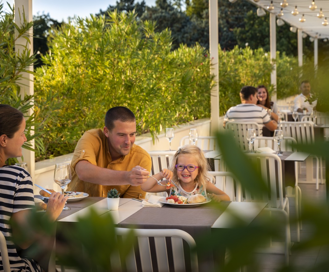 Family enjoying a meal at Magal Maradiso Hotel by Aminess restaurant.