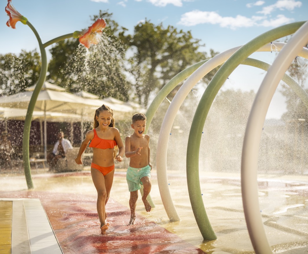 Djeća koja se igraju u vodenom igralištu u Aminess Atea Camping Resortu, savršenom za obiteljski odmor uz vodene fontane i zabavu
