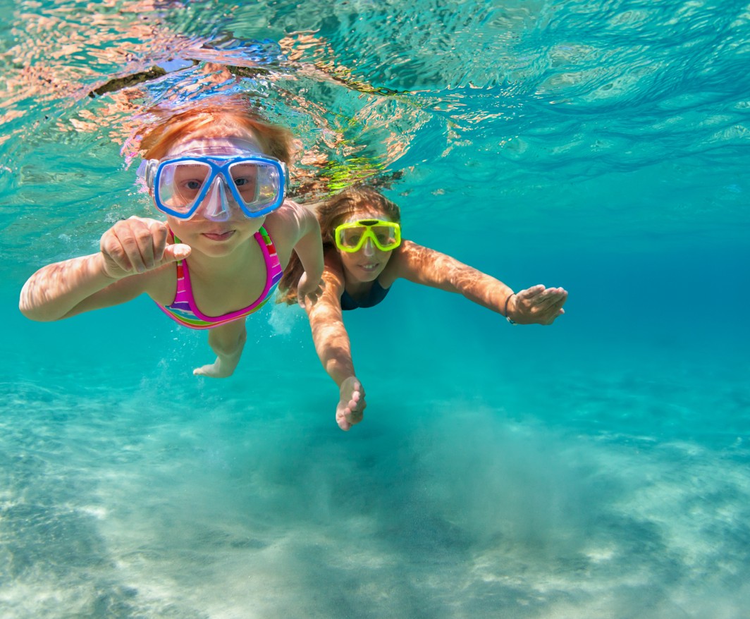 Ein Kind schnorchelt im kristallklaren Wasser am Aminess Port9 Planet Camping Korcula Strand, genießt ein Unterwasserabenteuer mit Maske und Schnorchel