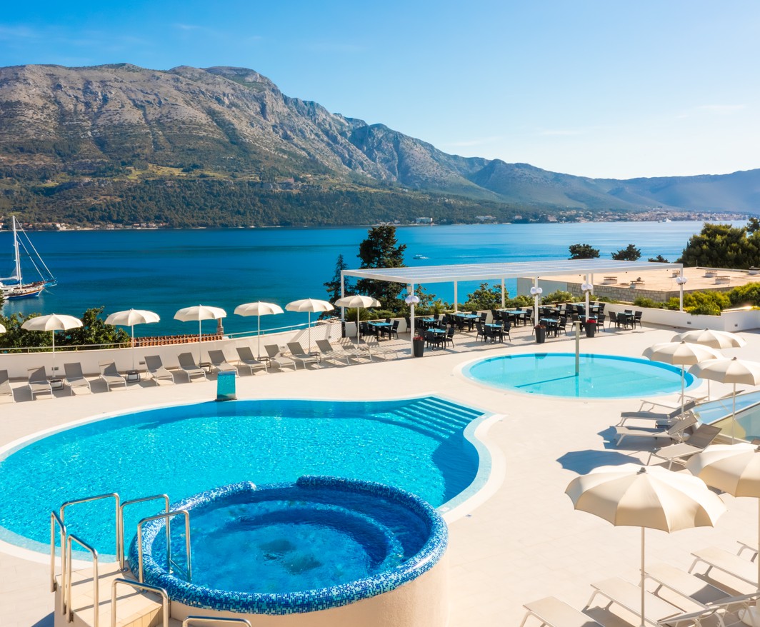 Glavni vanjski bazen hotela Marko Polo Mardiso s ležaljkama i impresivnim pogledom na planine.