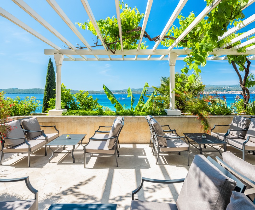 Überdachte Terrasse der Bar im Hotel Orsan in Orebić mit Panoramablick auf das Meer und viel Grün
