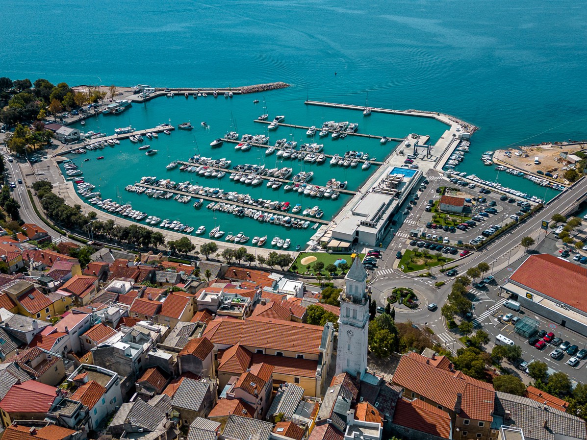 Seaside view of the marina and coastal town of Novi Vinodolski, Croatia, with boats and red rooftops.