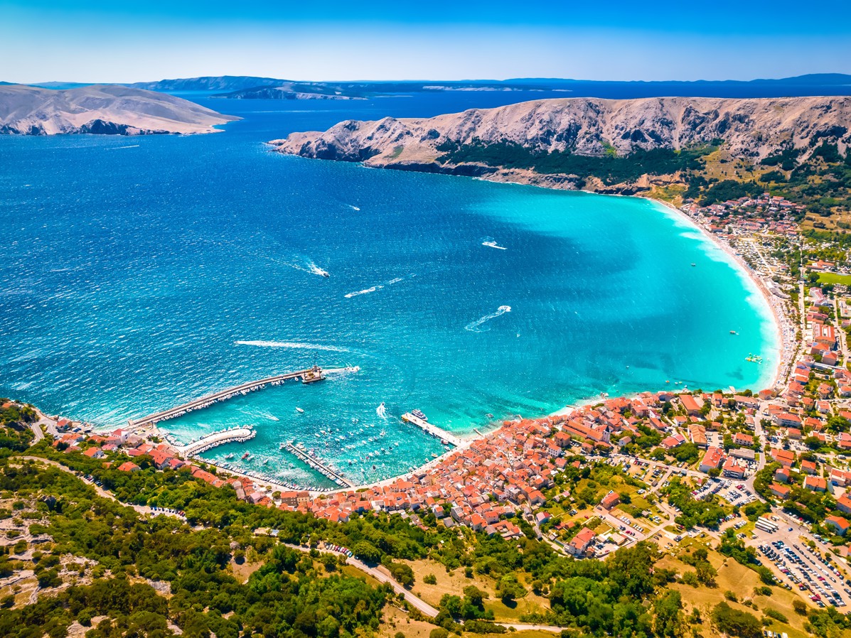 Panoramic view of Baška Bay on Krk Island, Croatia, a turquoise sea and green hills.
