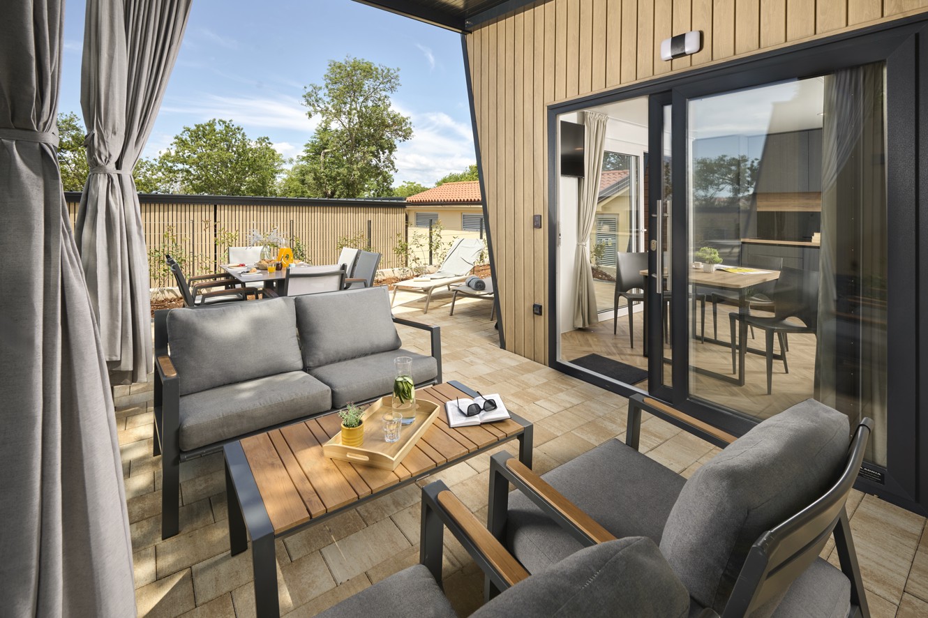 Patio van een luxe glamping villa met ligstoelen en groen