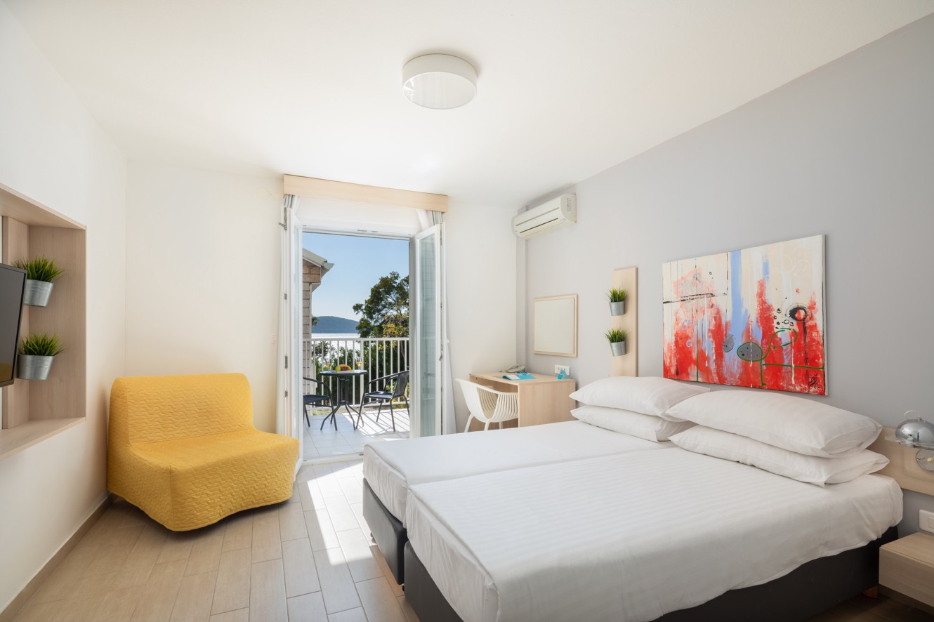 Ein helles und luftiges Zimmer im Aminess Maradiso Bellevue Village, mit einem komfortablen Bett und atemberaubendem Meerblick.