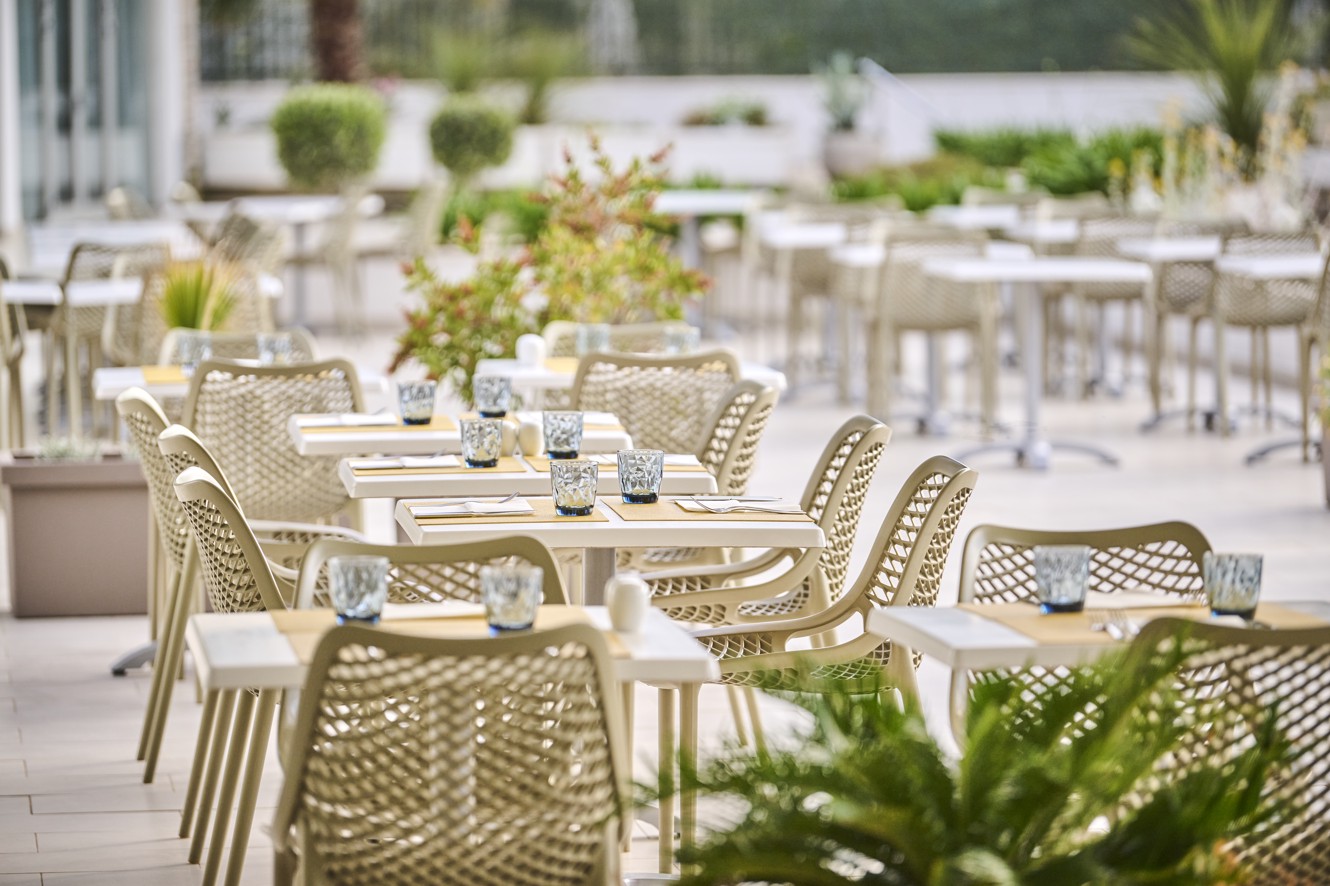 A table set with plates, cutlery, and glasses on the terrace, with a beautiful view of the surrounding area within resort near Aminess Vival Port9 Residence.