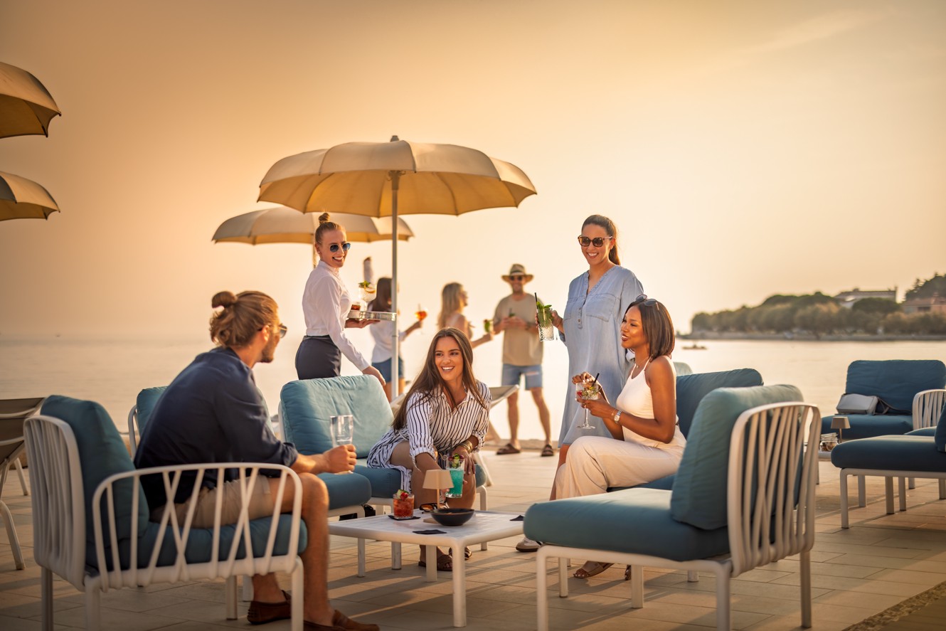 Persone che si rilassano sulla terrazza del bar con piscina infinity presso Aminess a Novigrad, Istria.